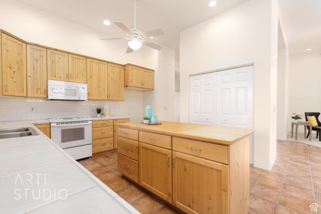Kitchen with decorative backsplash, light brown cabinets, white appliances, butcher block countertops, and a ceiling fan | Image 19
