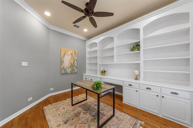 Office featuring ceiling fan, baseboards, light wood finished floors, built in desk, and ornamental molding | Image 11