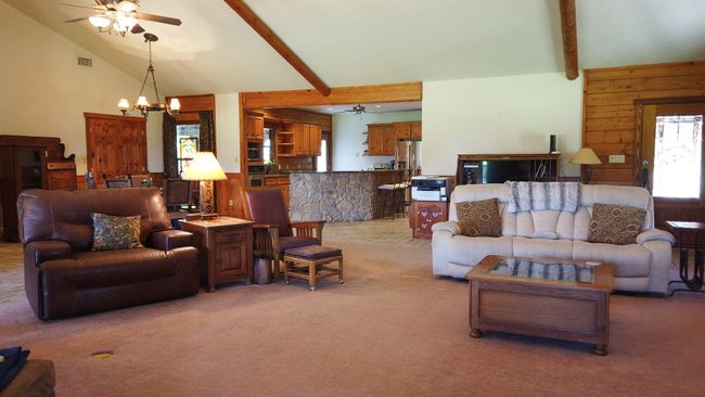 Living area with visible vents, ceiling fan with notable chandelier, light colored carpet, and beam ceiling | Image 10