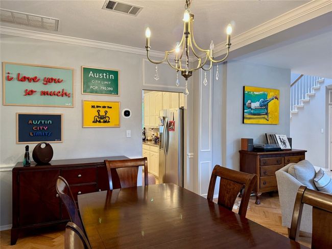 Dining room with visible vents, crown molding, stairway, and an inviting chandelier | Image 5