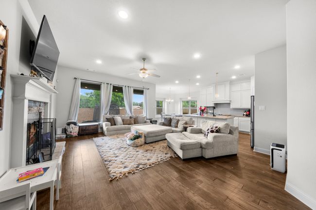 Living room featuring ceiling fan, plenty of natural light, a fireplace, recessed lighting, and dark wood-type flooring | Image 5