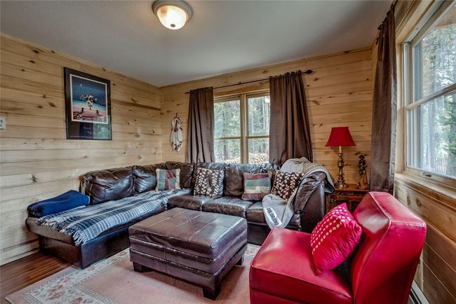Living area with healthy amount of natural light, wood walls, and wood finished floors | Image 19