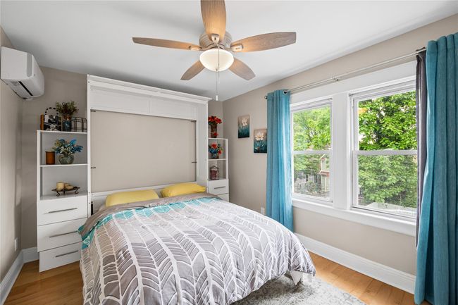 Bedroom featuring a wall mounted air conditioner, baseboards, and wood finished floors | Image 22