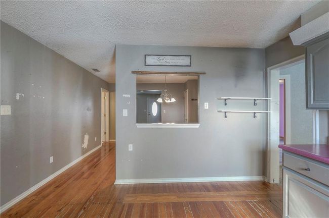 Kitchen featuring baseboards, a textured ceiling, gray cabinets, and wood-type flooring | Image 22