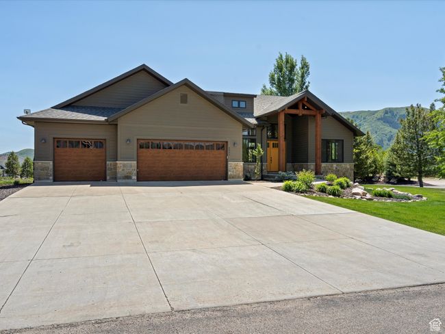 View of front of property with stone siding, an attached garage, concrete driveway, and a mountain view | Image 57