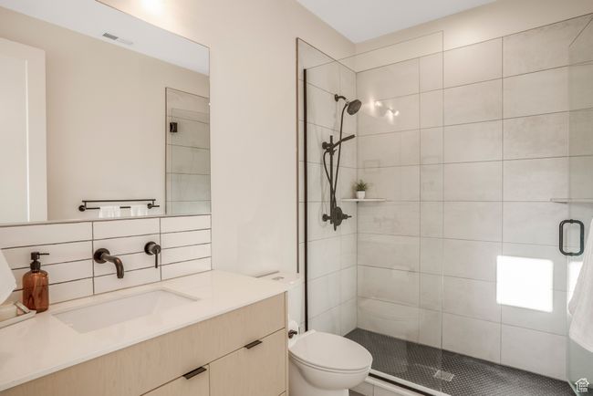 Full bathroom with a shower stall, vanity, visible vents, toilet, and decorative backsplash | Image 32