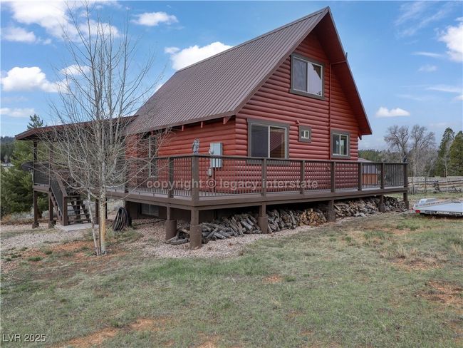 Back of property featuring a lawn, metal roof, log veneer siding, and a deck | Image 49