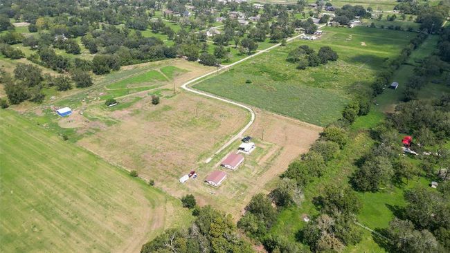 From above, the size and layout come into sharp focus. A well-worn path leads to the heart of the property, framed by trees, fields, and open potential. | Image 43
