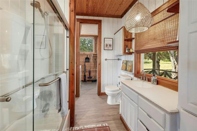 Bathroom with a stall shower, wood finished floors, wood ceiling, wooden walls, and vanity | Image 20