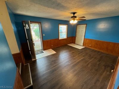 Entrance foyer with ceiling fan, wood walls, hardwood / wood-style floors, and a textured ceiling | Image 2