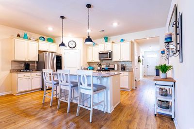 Kitchen with light hardwood / wood-style floors, stainless steel appliances, a center island, and a kitchen breakfast bar | Image 2