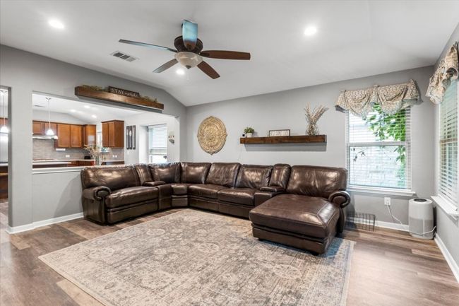 Living area featuring a ceiling fan, wood laminate floors, vaulted ceiling, baseboards, and recessed lighting | Image 15