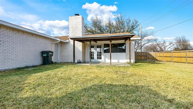 Rear view of house featuring a chimney, a patio area, brick siding, a fenced backyard, and a lawn | Image 29