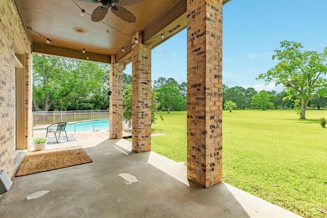 Enjoy the covered patio located just off the kitchen—perfect for outdoor dining and relaxing by the pool. | Image 37