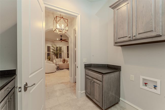 Washroom featuring cabinet space, washer hookup, a chandelier, arched walkways, and ceiling fan | Image 33