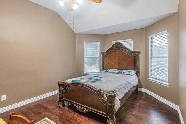 Bedroom featuring wood finished floors, vaulted ceiling, and a ceiling fan | Image 27