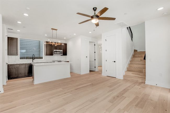 Kitchen with stainless steel microwave, dark brown cabinets, backsplash, light wood-type flooring, and recessed lighting | Image 19