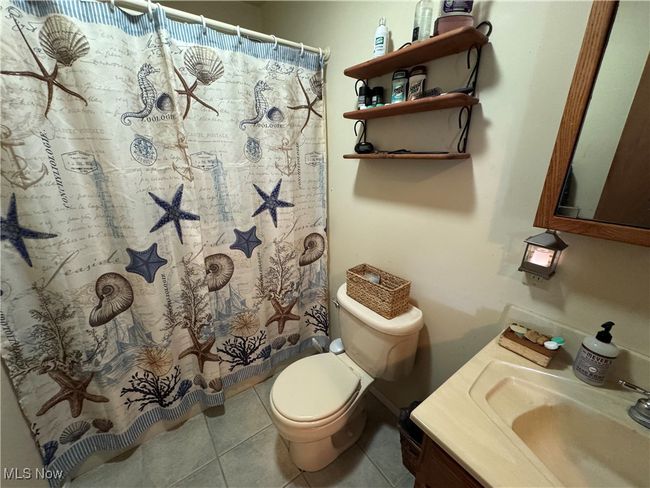 Bathroom featuring toilet, vanity, tile patterned floors, and a shower with curtain | Image 16