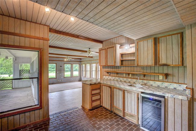 Kitchen featuring wine cooler, a sink, open shelves, light brown cabinetry, and brick patterned floors | Image 15