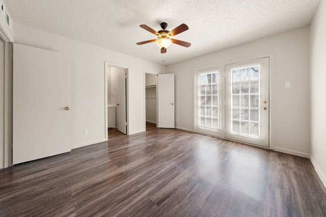 Unfurnished bedroom featuring access to exterior, a textured ceiling, dark wood-style floors, baseboards, and ceiling fan | Image 10