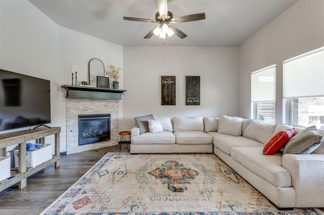 Living room with a glass covered fireplace, wood finished floors, and ceiling fan | Image 41