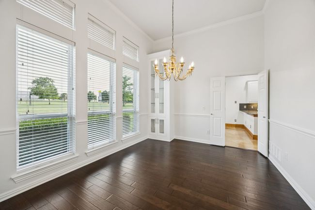 Dining room with a chandelier, ornamental molding, dark wood flooring, built-in cabinets, and a towering ceiling | Image 5