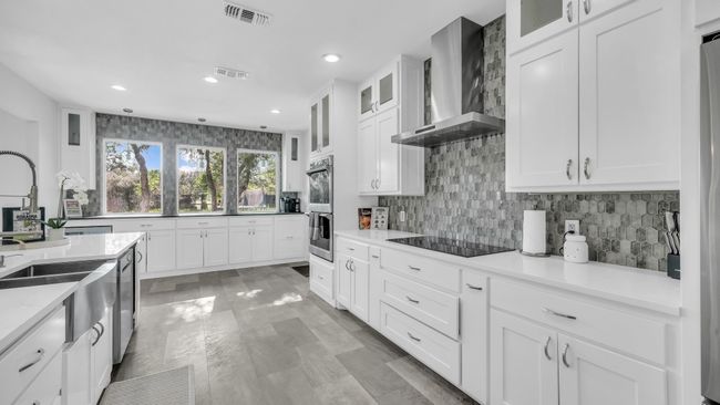 Kitchen featuring wall chimney range hood, stainless steel appliances, recessed lighting, white cabinetry, and tasteful backsplash | Image 10