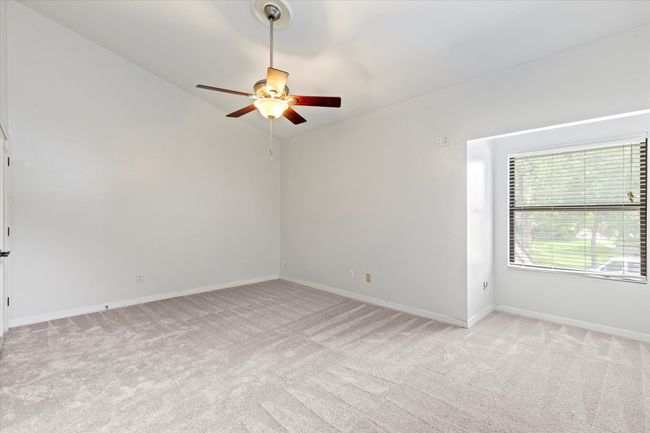 Spare room featuring light carpet, ceiling fan, baseboards, and lofted ceiling | Image 22