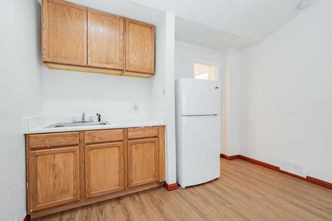 Kitchen featuring a sink, visible vents, freestanding refrigerator, light wood-style floors, and light countertops | Image 20