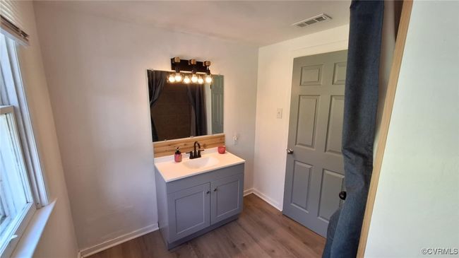 Bathroom featuring vanity, visible vents, baseboards, and wood finished floors | Image 33
