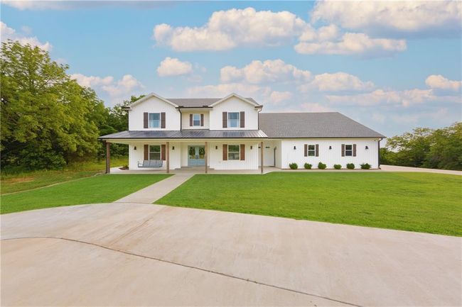 Modern farmhouse style home with a porch, a front lawn, driveway, roof with shingles, and metal roof | Image 5