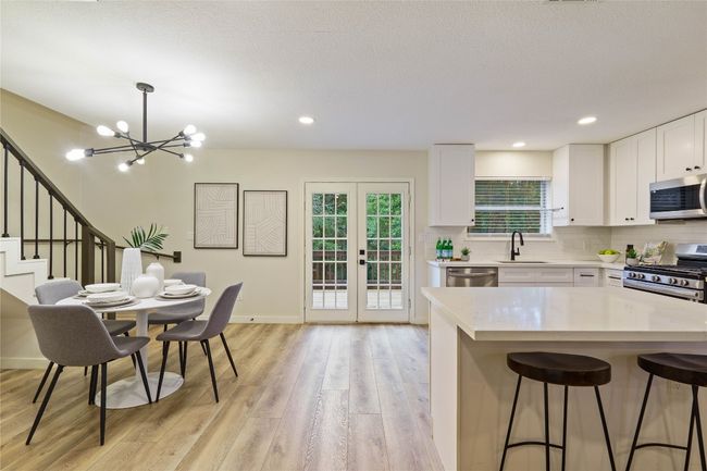 Kitchen featuring light wood-style floors, appliances with stainless steel finishes, light countertops, a notable chandelier, and a kitchen breakfast bar | Image 14