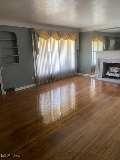 Unfurnished living room with hardwood / wood-style flooring, a premium fireplace, and a textured ceiling | Image 2