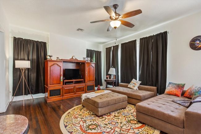 Living room with visible vents, ceiling fan, and dark wood finished floors | Image 18