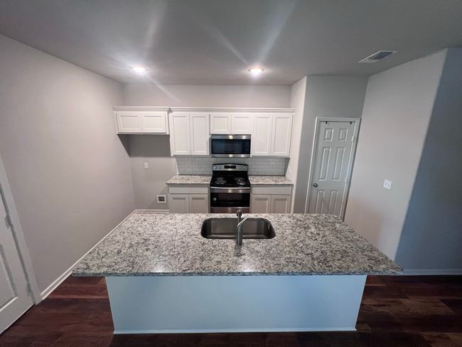 Kitchen with stainless steel appliances, a sink, light stone countertops, and recessed lighting | Image 15