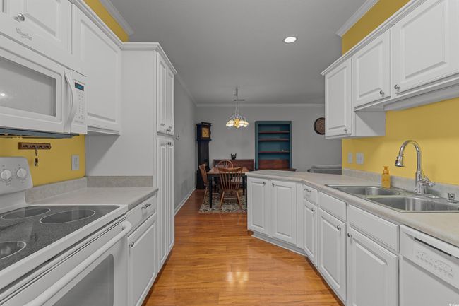 Kitchen featuring white appliances, a sink, white cabinetry, crown molding, and recessed lighting | Image 14
