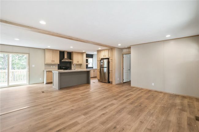 Kitchen featuring light wood finished floors, wall chimney range hood, light countertops, freestanding refrigerator, and open floor plan | Image 6