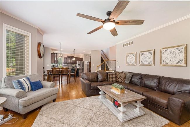 Living room with ceiling fan, ornamental molding, light wood-type flooring, and stairs | Image 11