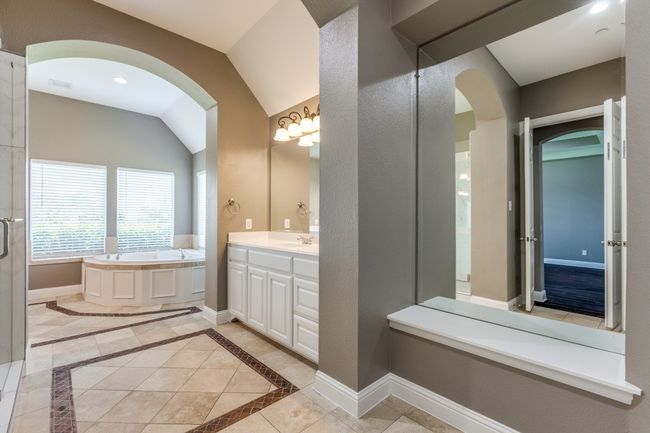 Primary bathroom featuring vanity, vaulted ceiling, a bath, and baseboards | Image 17