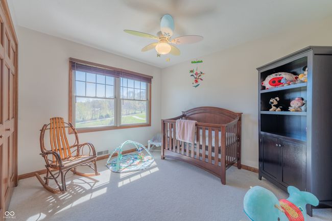 bedroom featuring a crib, ceiling fan, light carpet, baseboards, and visible vents | Image 26
