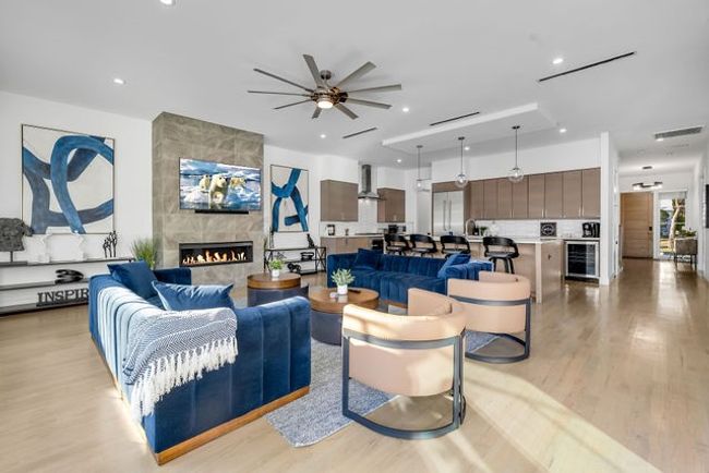 Living room featuring ceiling fan, a fireplace, beverage cooler, and light hardwood / wood-style flooring | Image 24