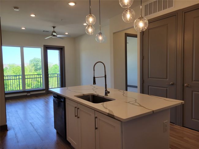 Kitchen with a sink, dishwasher, a ceiling fan, white cabinets, and dark wood-style flooring | Image 4