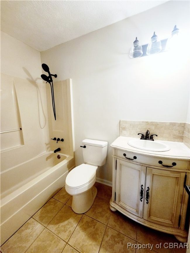 Full bathroom with a textured ceiling, tile patterned floors, shower / bathtub combination, and toilet | Image 9