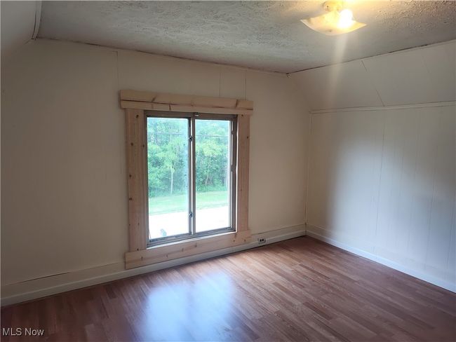 Spare room with wood finished floors, lofted ceiling, a textured ceiling, and baseboards | Image 42