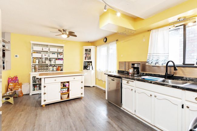 Kitchen featuring dishwasher, white cabinets, a ceiling fan, dark countertops, and wood finished floors | Image 13