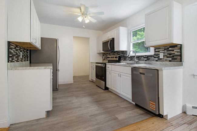 Kitchen featuring appliances with stainless steel finishes, a sink, ceiling fan, tasteful backsplash, and white cabinets | Image 12
