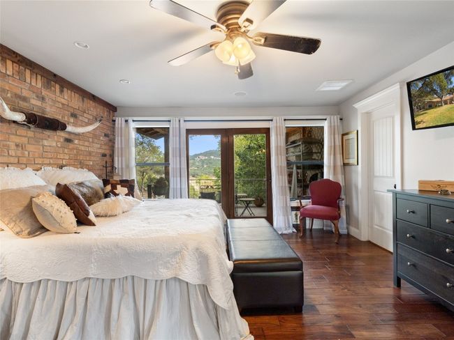 The owners suite features 2 closets, a brick accent wall and french doors opening to the patio. | Image 5