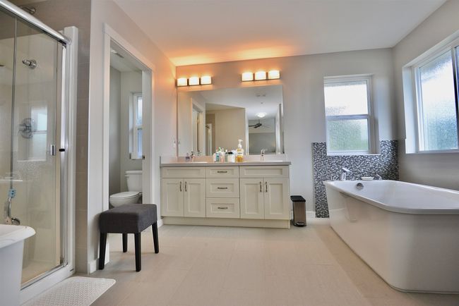 Bathroom featuring double vanity, a stall shower, a soaking tub, and ceiling fan | Image 25