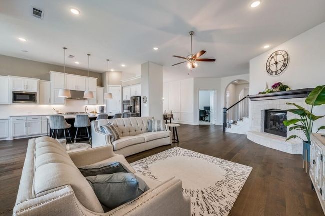 Living room with dark wood-style flooring, arched walkways, a ceiling fan, recessed lighting, and a glass covered fireplace | Image 38