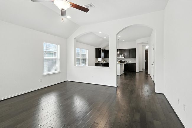 Unfurnished living room with vaulted ceiling, a ceiling fan, arched walkways, dark wood finished floors, and recessed lighting | Image 24